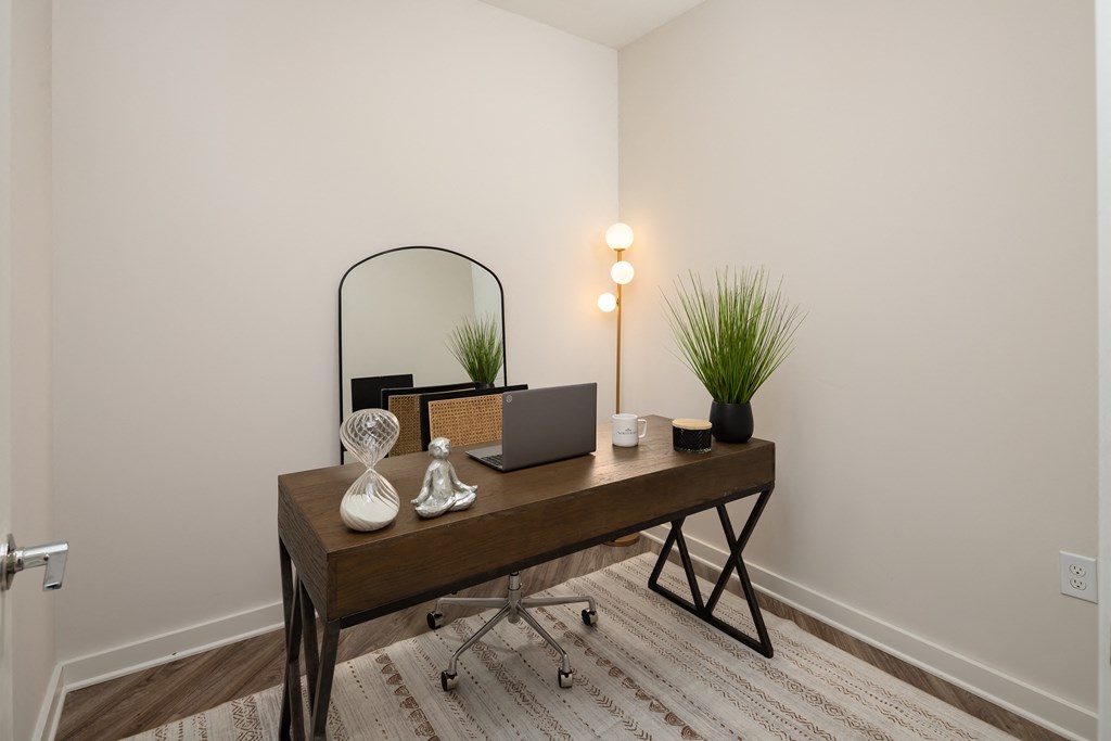 a bedroom with a desk with a laptop and a mirror