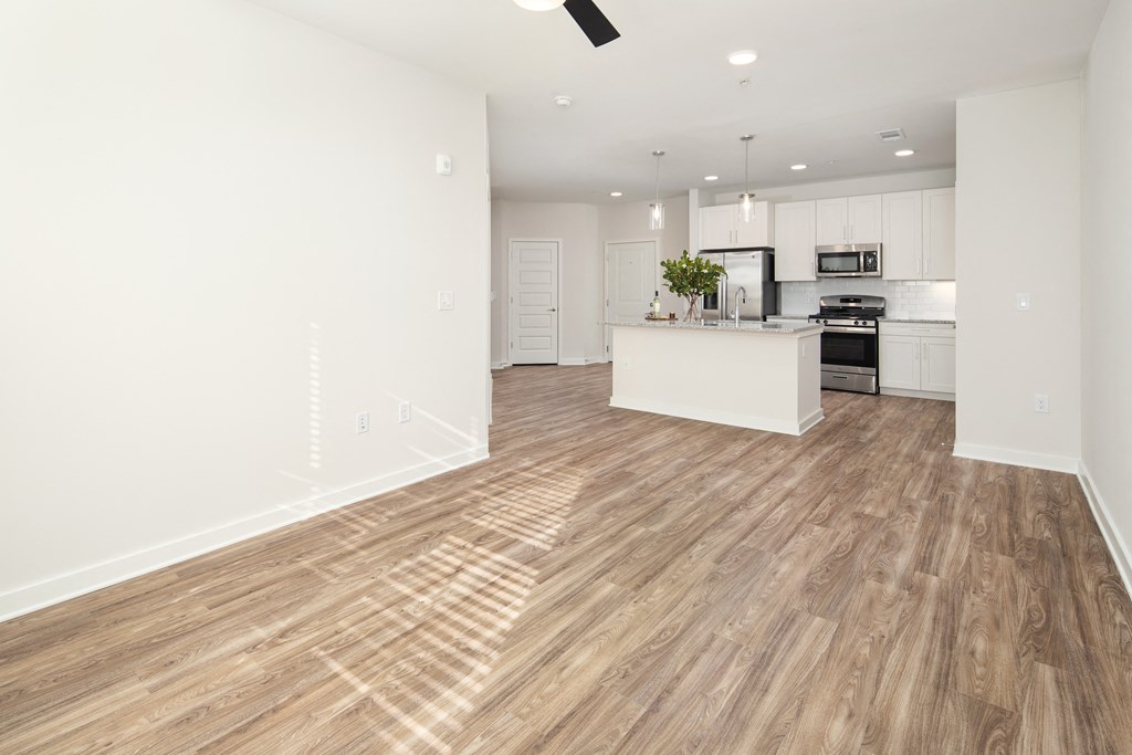 an open kitchen and living room with white walls and wood flooring