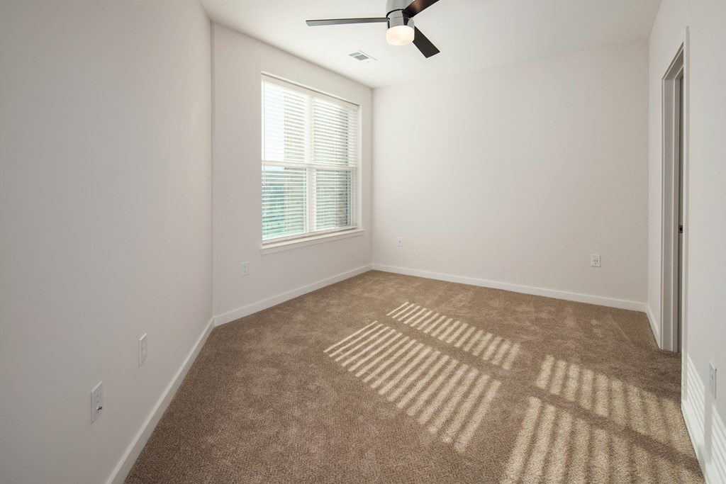 an empty living room with a window and a ceiling fan