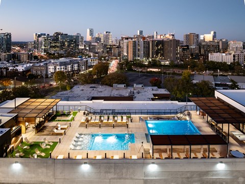 A rooftop pool area with a city skyline in the background.
