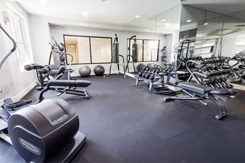 a gym with weights and other equipment on the floor and mirrored walls
