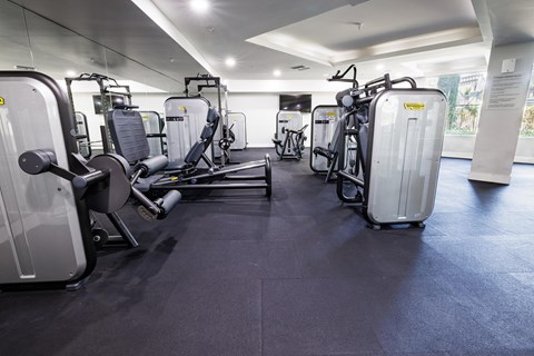 a gym with various exercise machines and luggage on the floor