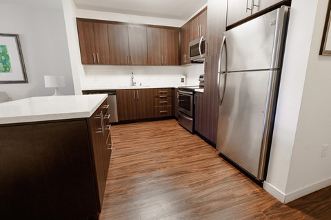 an empty kitchen with stainless steel appliances and wooden flooring