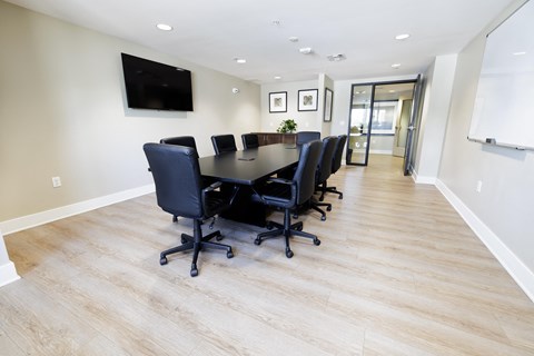 a conference room with a long table and chairs and a tv