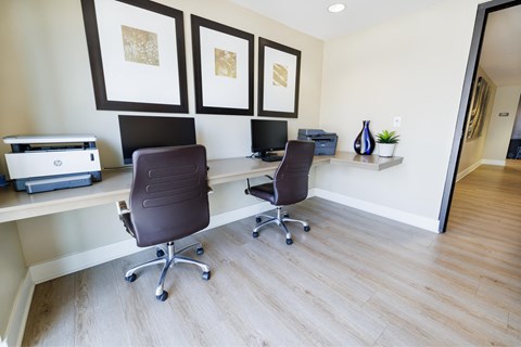 a home office with two desks and two chairs and a printer