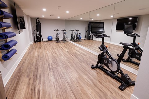 a gym with cardio machines and weights on a wooden floor