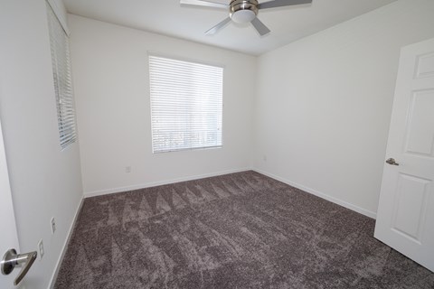 an empty room with carpet and a ceiling fan