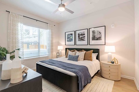 A bedroom with a bed, nightstand, and a ceiling fan.