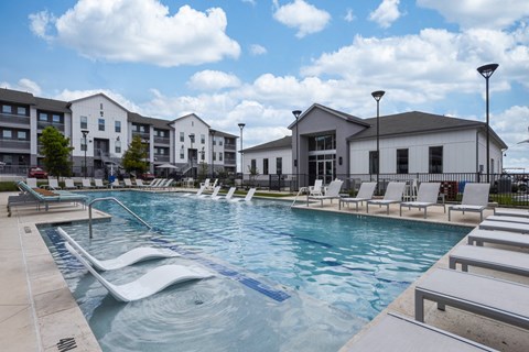 A swimming pool with lounge chairs and a building in the background.