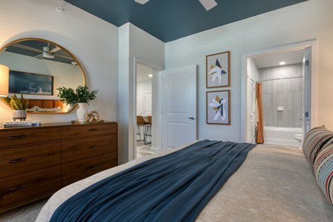 A bedroom with a large bed and a dresser with a mirror above it.