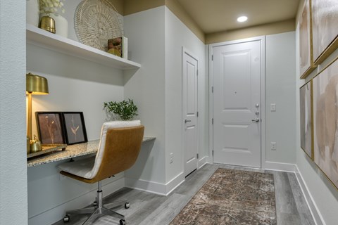 A hallway with a chair and a plant on a desk.