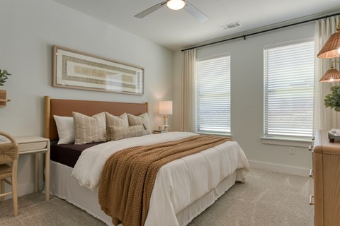 A bedroom with a large bed and a ceiling fan.