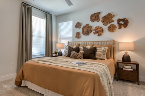 A bedroom with a bed, nightstand, and a wall decoration of wooden carvings.
