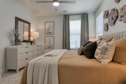 A bedroom with a large bed, a dresser, and a ceiling fan.