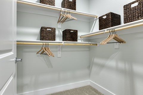A white closet with hangers and baskets on shelves.