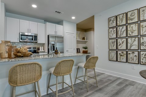 A kitchen with a counter and chairs.