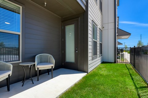 A patio with a chair and table outside a house.
