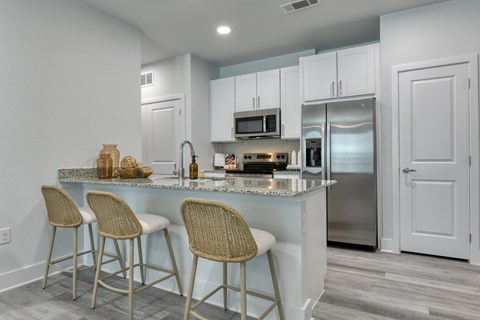 A kitchen with a white counter and bar stools.