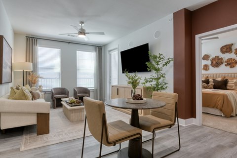 A living room with a white couch, a brown chair, and a television on the wall.