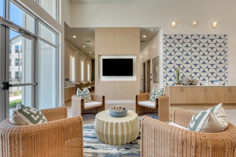 A living room with a television, wicker chairs, and a patterned wallpaper.