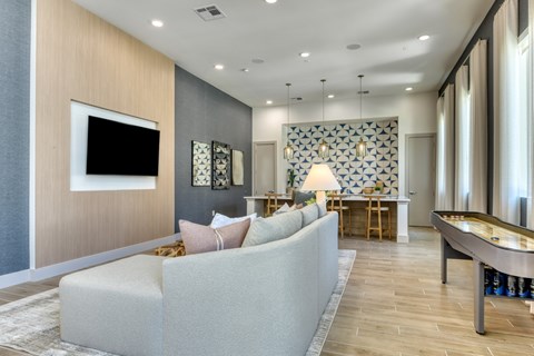 A modern living room with a grey sofa and a pool table.