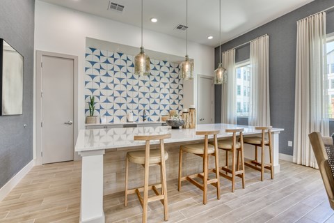 A kitchen with a white island and wooden chairs.
