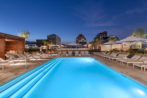 A long rectangular pool with lounge chairs on the side.