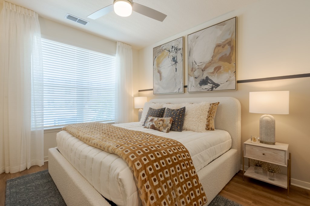 A bedroom with a bed, nightstand, and two wall art pieces.