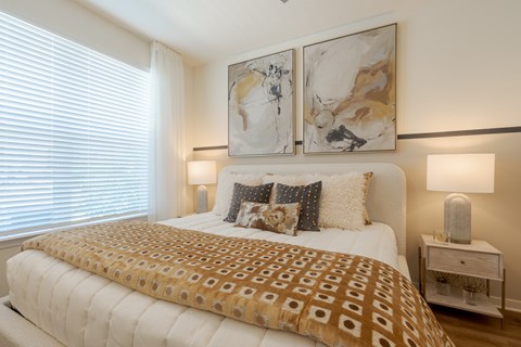 A bedroom with a large bed and two lamps.