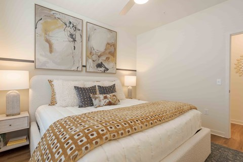 A bedroom with a large bed and two wall art pieces.