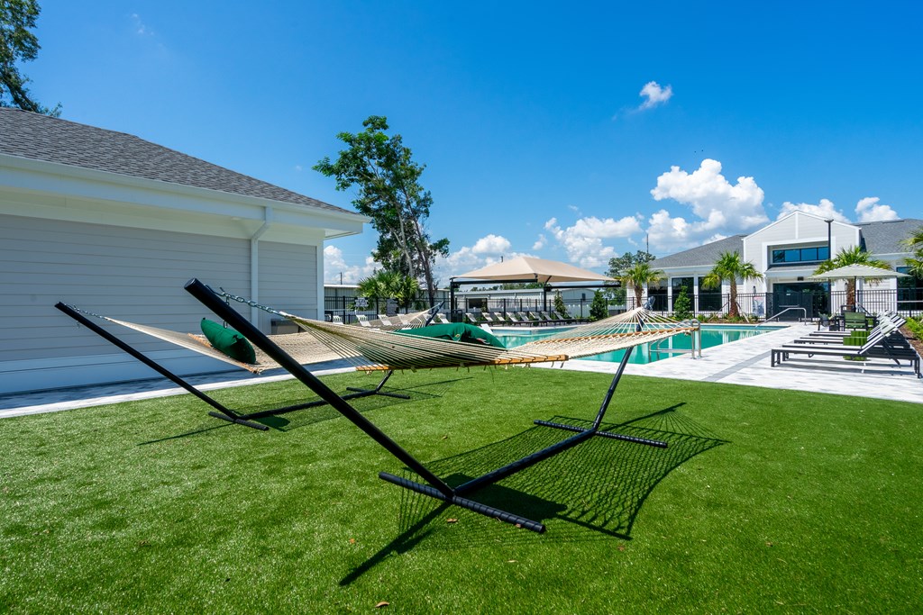 A lawn chair is on a green lawn in front of a house.