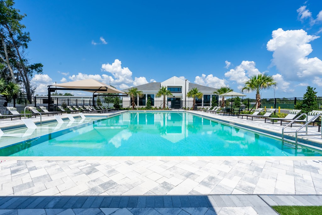 A large swimming pool with a tiled edge and a building in the background.