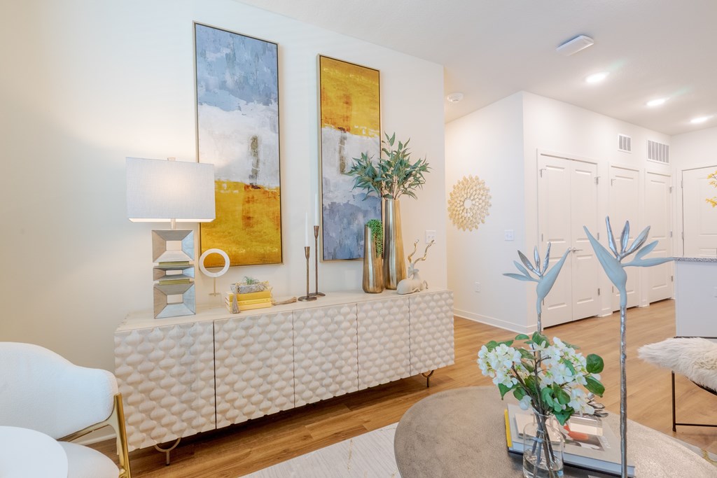 A living room with a white sofa and a painting on the wall.