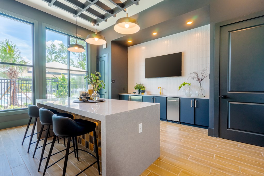 A kitchen with a bar area and a flat screen TV mounted on the wall.