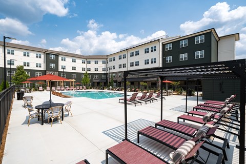 A pool area with a table and chairs and a building in the background.