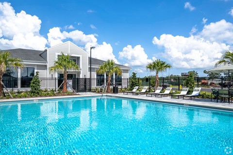 A swimming pool in front of a building with palm trees.