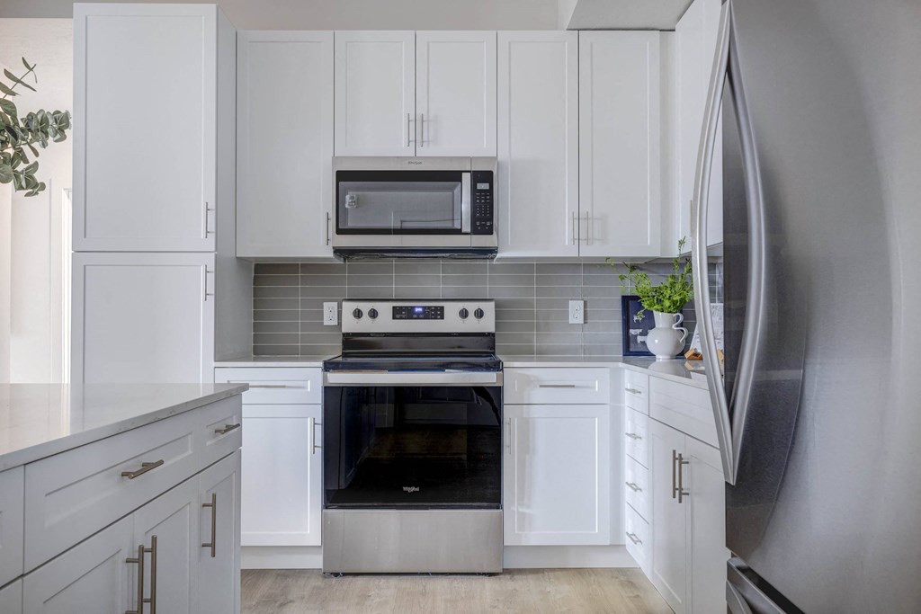 a white kitchen with stainless steel appliances and white cabinets