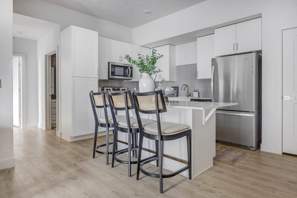 a kitchen with a bar with three stools
