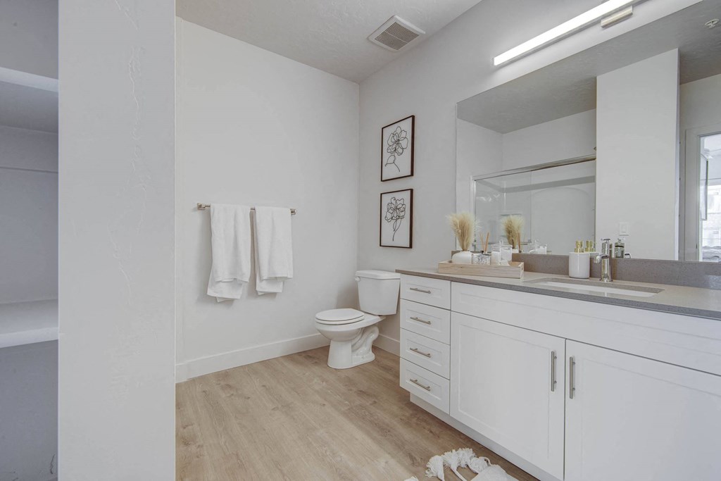 a white bathroom with a large mirror and a toilet