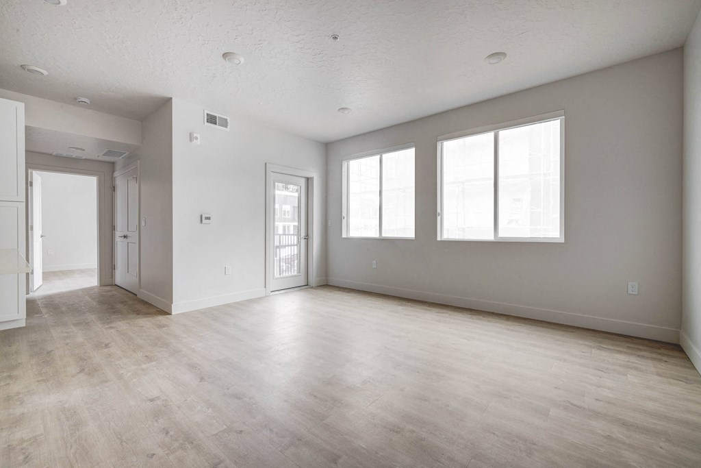 the living room and dining room of an empty apartment with white walls and wood floors