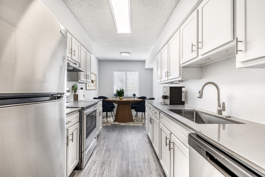 a large kitchen with white cabinets and stainless steel appliances and a dining room table