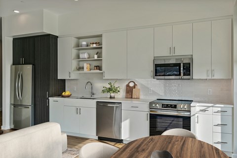 A modern kitchen with white cabinets and a wooden island.