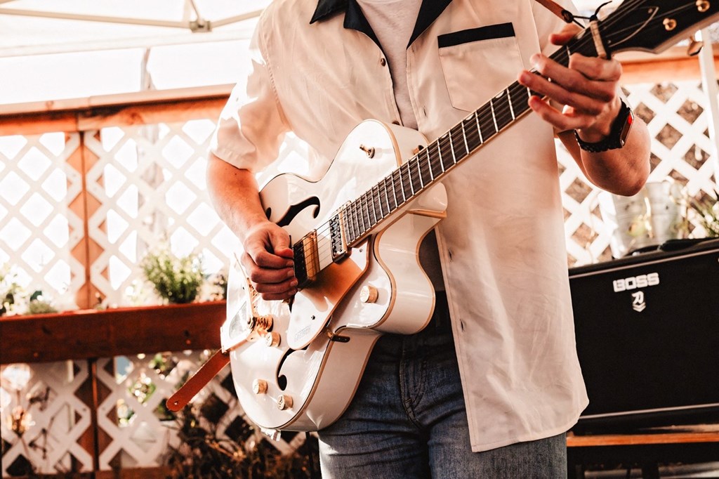 a man holding a white guitar and a cell phone