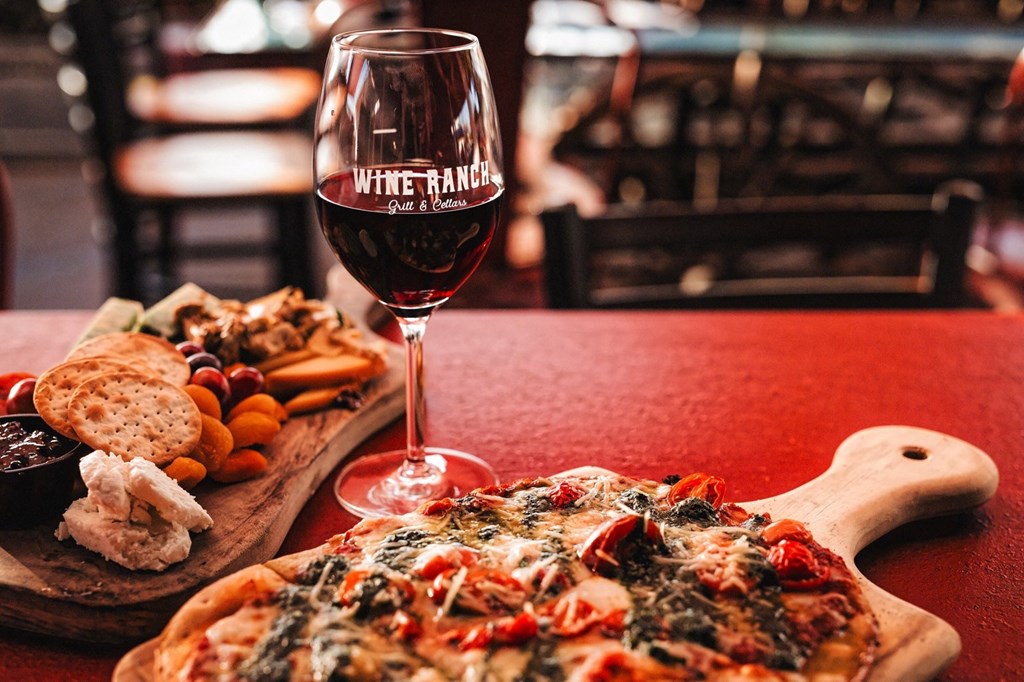 a pizza and a glass of red wine on a table