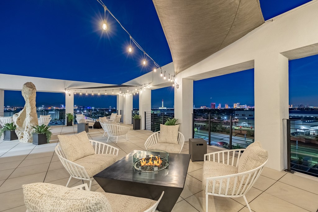 the terrace has a fireplace and a view of the city at night