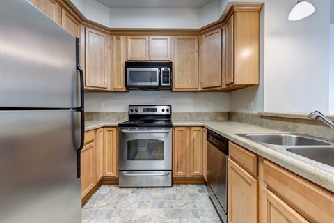 A kitchen with wooden cabinets and a stainless steel refrigerator.