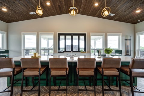 a kitchen with a bar and chairs in front of a row of windows