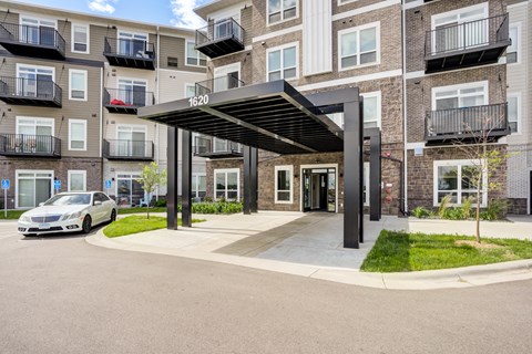 an apartment building with a car parked under awning