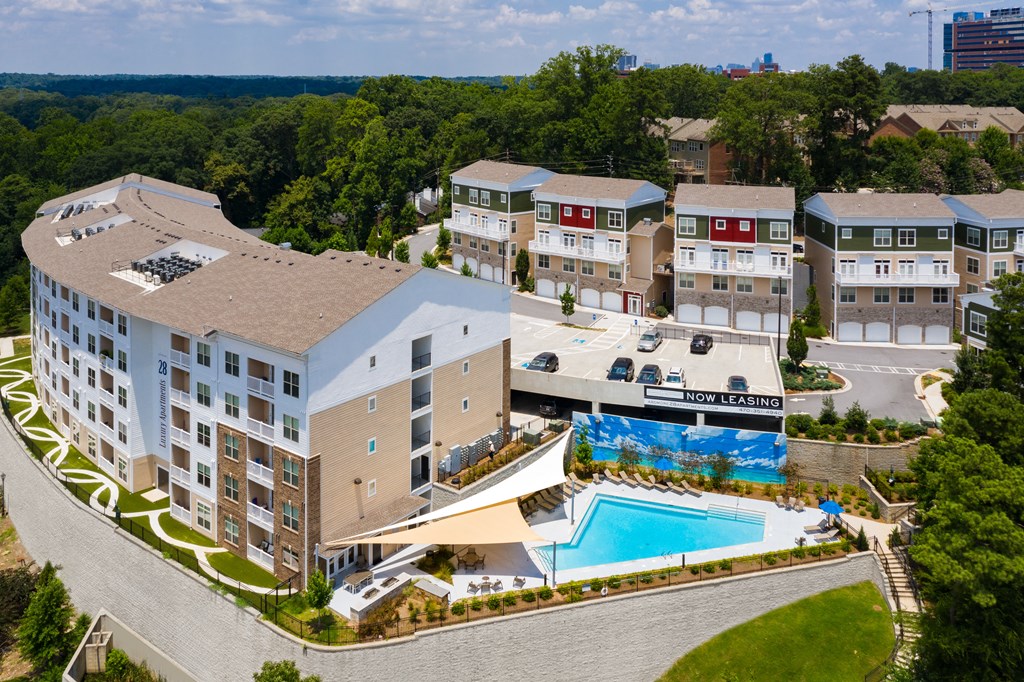 A large apartment complex with a swimming pool and a sign that says "Now Leasing".