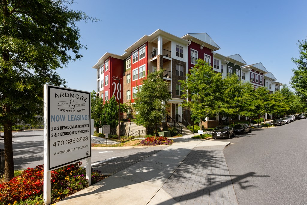 A sign for Ardmore Apartments is in the foreground of a street with apartment buildings in the background.